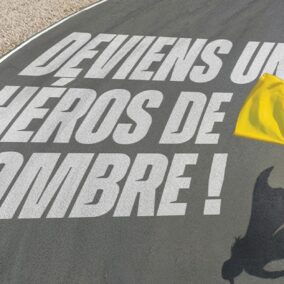 Commissaire de piste avec drapeau jaune sur circuit mettant en avant le rôle des héros de l’ombre en sport moto