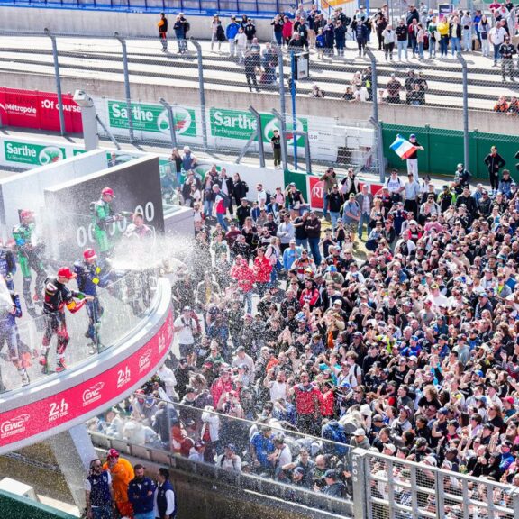 Podium des 24 Heures Motos 2026 : le YART Yamaha Official EWC Team fête sa victoire au champagne devant une foule dense au Mans